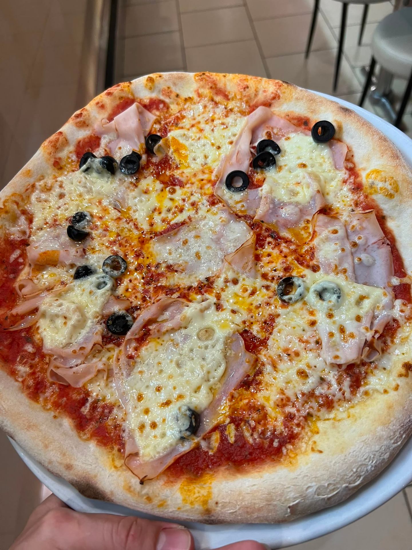 Wood-fired pizza with ham and olives